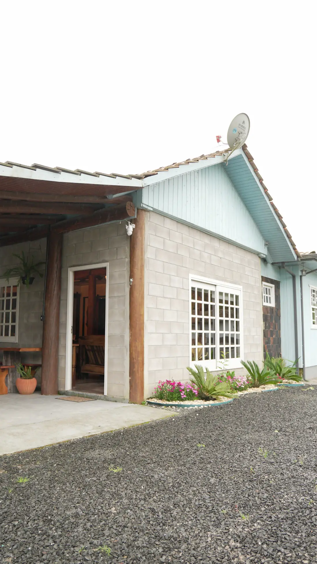 Fachada da pousada com janelas brancas e flores